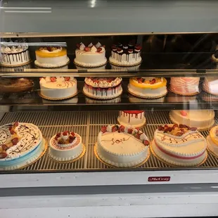 a variety of cakes in a display case