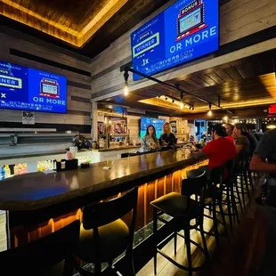 people sitting at the bar watching televisions