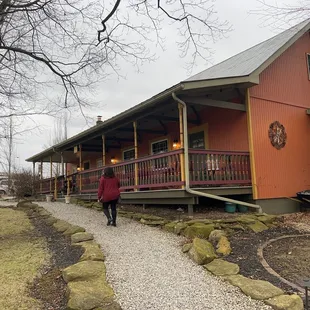 a woman walking towards a red house