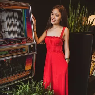 a woman in a red dress standing next to a slot machine