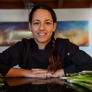 a woman sitting at a table with vegetables