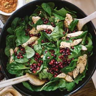 a bowl of spinach, chicken, and meat skewers