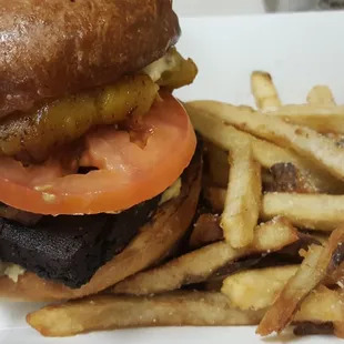 Crazy Jamaican Burger with plantains, tofu, potato salad, grilled onions, tomatoes, and aioli with a side of fries.