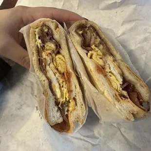 a hand holding two sandwiches