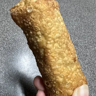 a hand holding a fried pastry