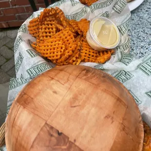 a table with a basket of waffles and a plate of fries