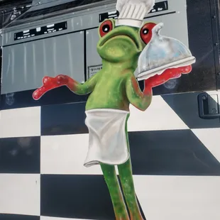  frog with a chef's hat and apron holding a clochet