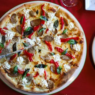 Vesuvio Pizza. Topped with Italian sausage, ricotta, basil, roasted peppers, mozzarella cheese and olive oil drizzle