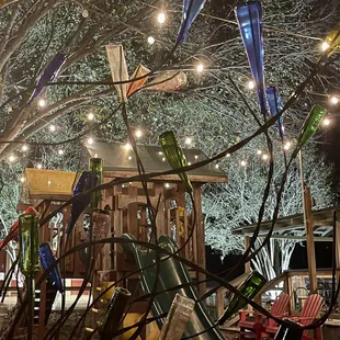 Glass sculpture in front of kids playground under decorative lights