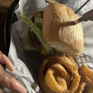 a hamburger and onion rings in a basket
