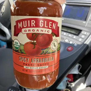 a person holding up a jar of sauce