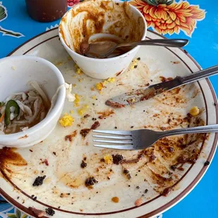 a plate of food with a fork and a bowl of noodles