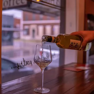 a person pouring a glass of wine