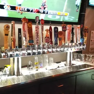 beer taps on a bar with a television in the background