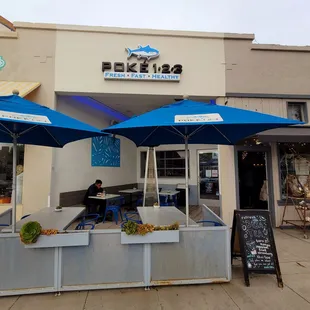 he outside of a restaurant with blue umbrellas