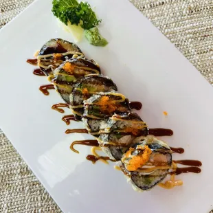 a plate of sushi with sauce and broccoli