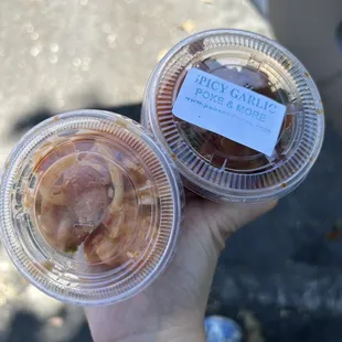 a hand holding two cups of food