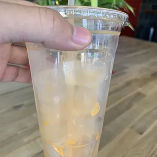 a hand holding a plastic cup filled with ice and a straw