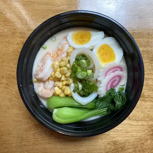 Seafood Noodle Soup. Topped with corn, scallions, greens, bamboo shoots, fish cake, and a soft boiled egg.