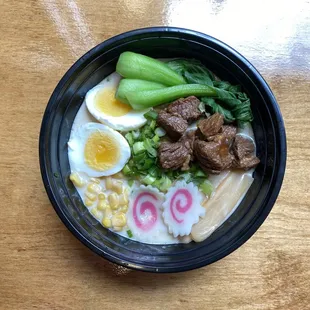 Braised Beef Noodle Soup. Topped with corn, scallions, greens, bamboo shoots, fish cake, and a soft boiled egg.