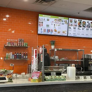 a restaurant counter with a menu on the wall