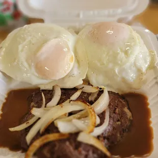 two eggs on top of a steak with gravy