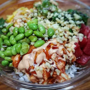 Spicy tuna and marinated tuna over rice base, edamame, seaweed salad, mango, Krab  salad, eel sauce, spicy mayo, and panko crunchies