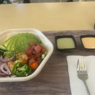 Spicy salmon and marinaded tuna poke bowl on bed of greens.