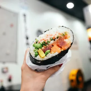 a hand holding a sushi roll