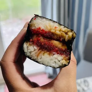 a hand holding a piece of sushi