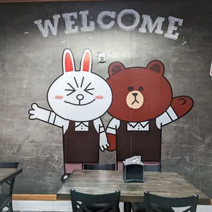 a table and chairs with a welcome sign on the wall