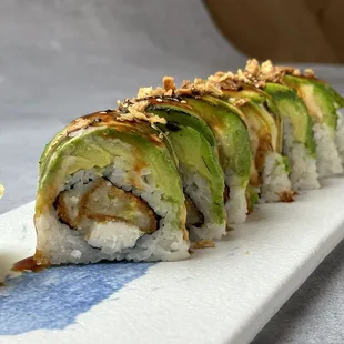 a sushi roll with avocado and pine nuts