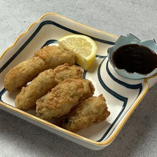 a plate of fried fish with a side of dipping sauce
