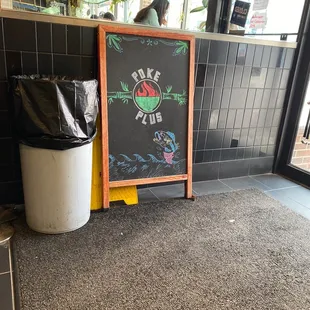 a chalkboard sign and trash can