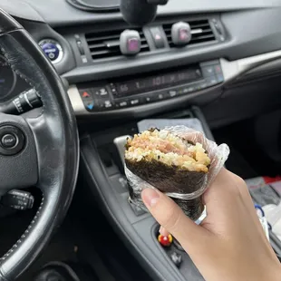a hand holding a burrito in a car