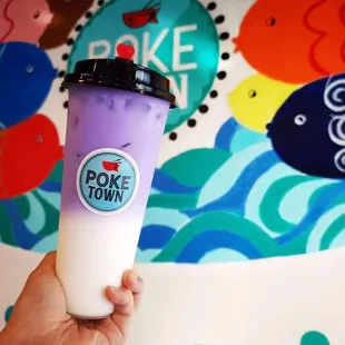 a hand holding a cup of poke town