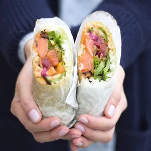 a woman holding two burritos