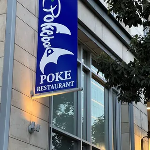 a blue and white sign hanging from the side of a building