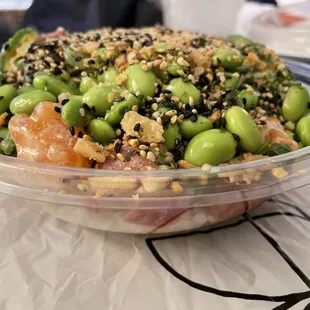 a bowl of salad with edamado, oranges, and sesame seeds