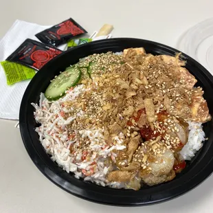 White rice, salmon with spicy sauce, scallops with mango sauce, tobiko, crab, cucumbers, garlic, toasted sesame seeds.