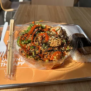 a bowl of food on a tray with chopsticks
