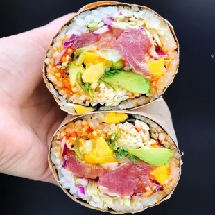 a hand holding two sushi rolls