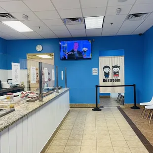 a view of a restaurant counter with a television on the wall