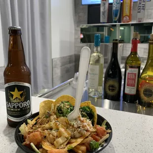 Fresh Salmon poke with nachos and delicious toppings paired with a cold refreshing Sapporo beer.