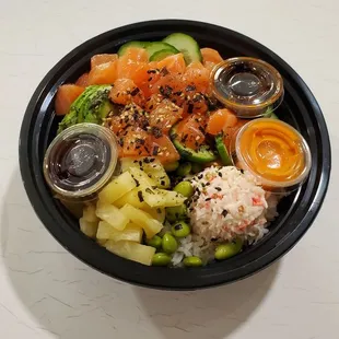 Rice, salmon, Yuzu ponzu, Sweet Eel, Spicy mayo sauce, Cucumber, Crab meat, Pineapple, Edamame, Avocado topped with seaweed sesame mix.