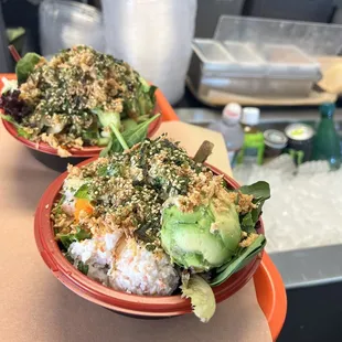 2 small bowls the front is with a scoop of avocado crab meat. It is half salad and white rice with lots of selected toppings.