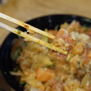 a person holding chopsticks over a bowl of food
