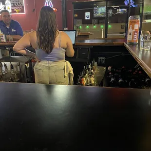 a woman standing at a bar with a man behind her