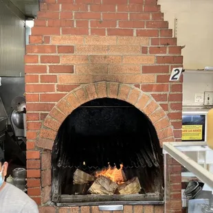 a man wearing a face mask in front of a brick oven