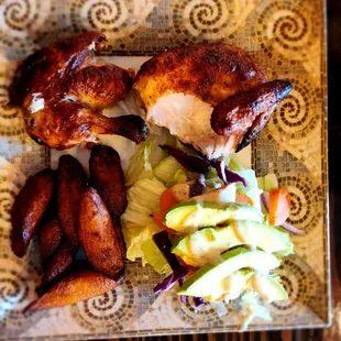 Half chicken with fried sweet plantains, and avocado salad.